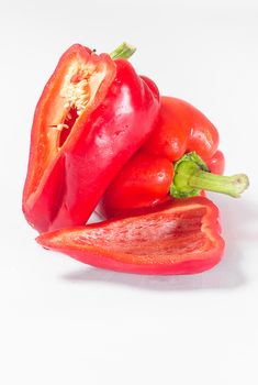 A whole pepper and pepper slices on a white background with a green sprig
