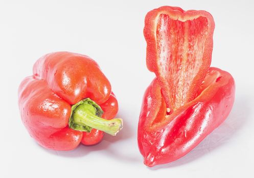 A whole pepper and pepper slices on a white background with a green sprig