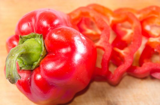 Red pepper cut by slice on a wooden background. Horizontal photo