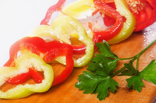 Sliced red and green peppers on a wooden background with parsley