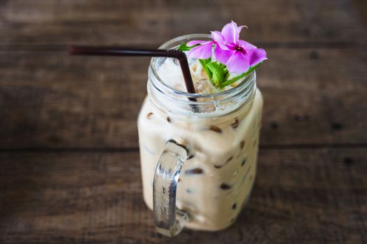 Iced coffee in vintage jar and flower decoration, selective focus