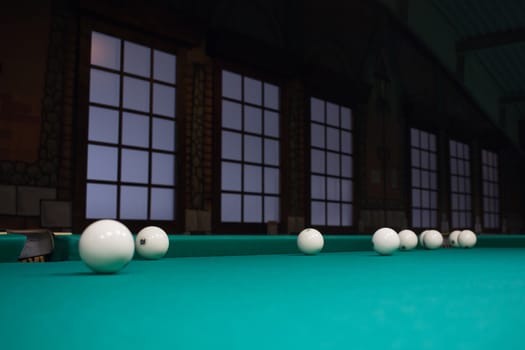 Russian billiards balls on green game table cloth in the middle of game with windows on background