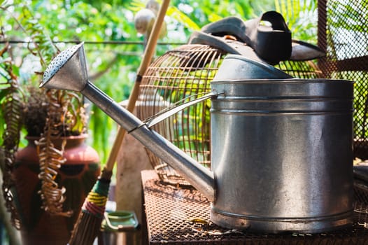 Watering can on rusty table, bird cage background