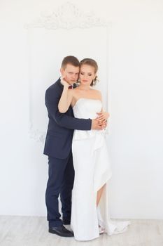 Stylish newly-married couple standing embracing in bedroom