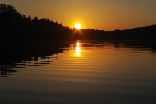 a orange sunset over a european lake, blue clouds sky, colored dramatic landscape scene