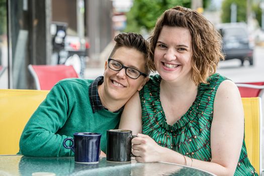 Woman leaning on shoulder of female spouse at outdoor coffee house