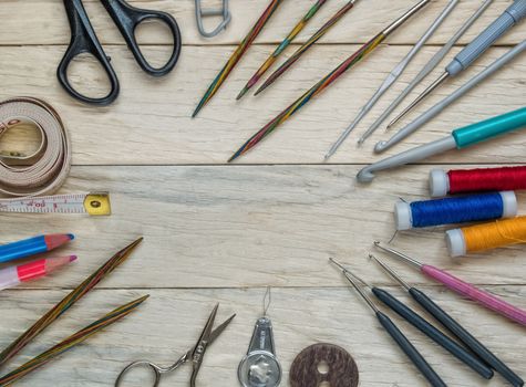 Accessories for sewing and crochet beautifully lie on a wooden table in the background