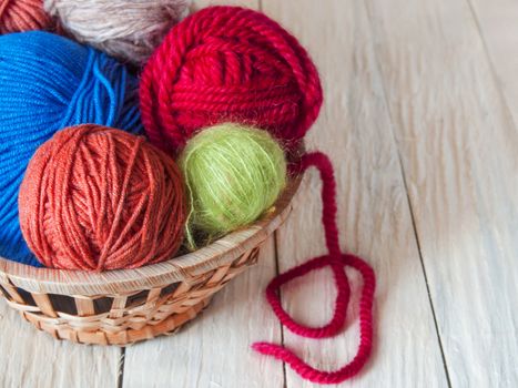 Yarn for hand knitting in different colors, needles, hooks lie on a wooden table