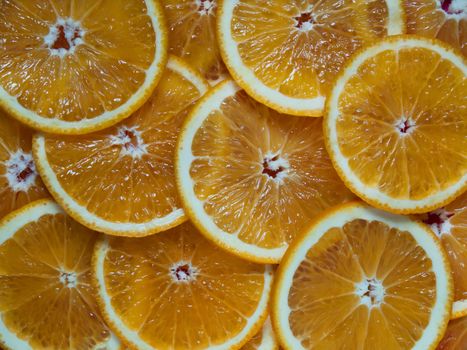 Orange sliced into thin round slices and lies on a table on a wooden background