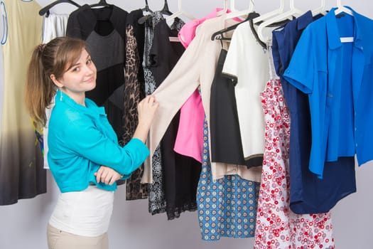 Young girl chooses clothes in the wardrobe, and looked into the frame