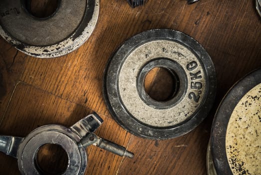 Detail Of Some Vintage Gym Dumbbell Weights Against A Rustic Wooden Floor