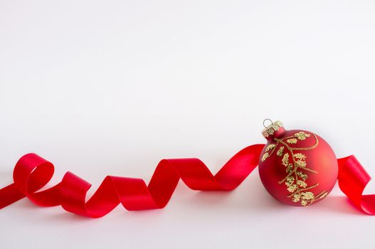Red christmas ball with ribbon on white background. Space for copy.