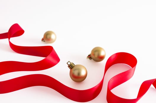 Golden christmas balls with red ribbon on white background.