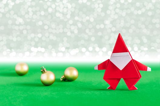 Santa Claus paper craft and golden ball with lights snow winter background. Paper origami.