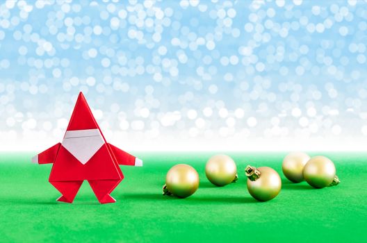 Santa Claus paper craft and golden ball with lights snow winter background. Paper origami.