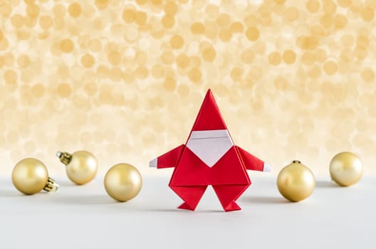 Santa Claus paper craft and golden ball with lights snow winter background. Paper origami.