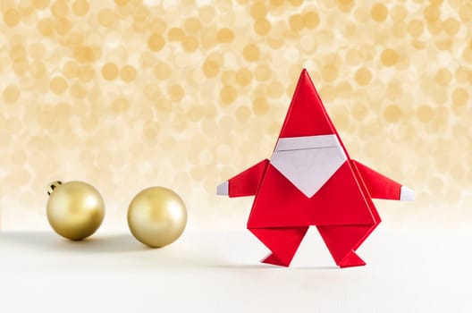 Santa Claus paper craft and golden ball with lights snow winter background. Paper origami.