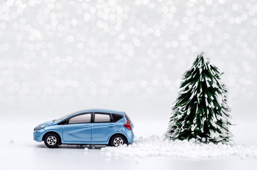 Christmas tree and blue car with lights snow winter background. Christmas holiday celebration concept.
