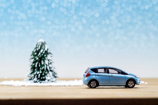 Christmas tree and blue car with lights snow winter background. Christmas holiday celebration concept.