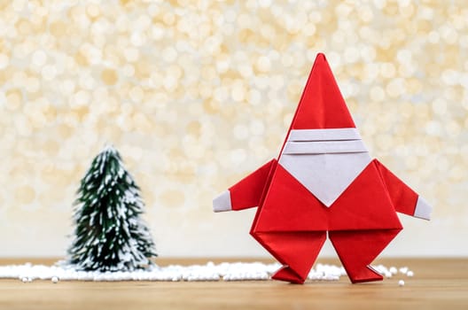 Santa Claus paper craft and christmas tree with lights snow winter background. Paper origami.