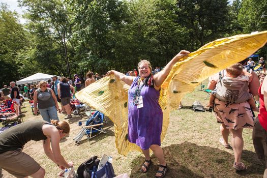 HOT SPRINGS, NC - JULY 10: Joyful woman in purple dress flying with bird wings at the Wild Goose Festival on July 10, 2016 in Hot Springs, NC, USA.