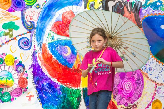 HOT SPRINGS, NC - JULY 10: Cute girl in pink twirling her umbrella in front of banner at the Wild Goose Festival on July 10, 2016 in Hot Springs, NC, USA.