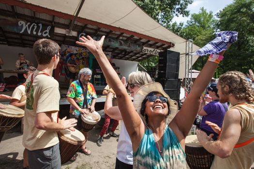 HOT SPRINGS, NC - JULY 10: Happy adult woman in hat and sunglasses rejoicing with arms up at the Wild Goose Festival on July 10, 2016 in Hot Springs, NC, USA.