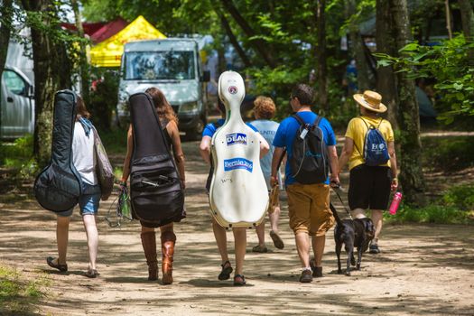 HOT SPRINGS, NC - JULY 8: Rear view of musicians walking with their string instrument cases as the Wild Goose Festival on July 8, 2016 in Hot Springs, NC, USA.