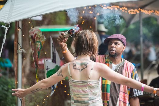 HOT SPRINGS, NC - JULY 8: Bearded shaman moves smudge stick around woman at the Wild Goose Festival on July 8, 2016 in Hot Springs, NC, USA.