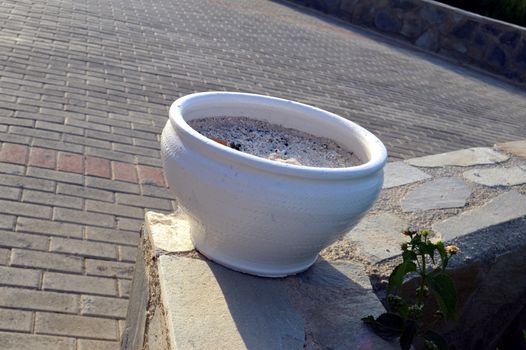 A white outside ashtray on a stone wall