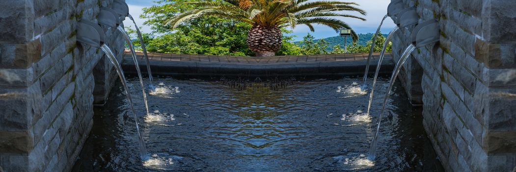 Modern fountain with six spotlighted water in the background sea and countryside.