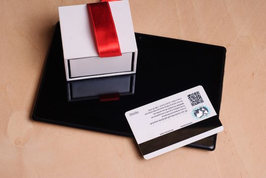 Credit card and electronic tablet on wooden table, gift with red ribbon, online shopping