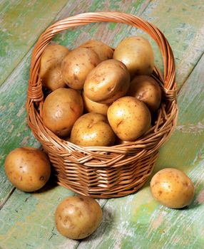 Heap of Fresh Raw Small Potatoes in Wicker Basket closeup on Cracked Wooden background