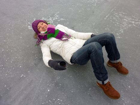 a young smiling woman is lying on ice, frozen lake - winter outdoor scene