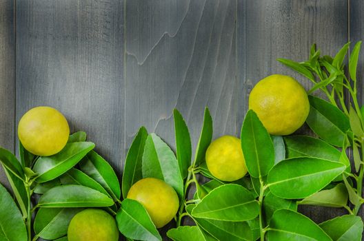 top view of wooden background with fresh lime and green leaves