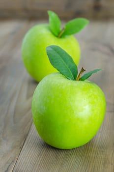 Ripe green apple with leaf  on a wooden background