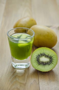 glass of kiwi juice with fresh fruits on wooden table