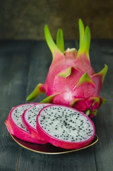 Ripe Dragon fruit  with slice on dish over wooden background , still life