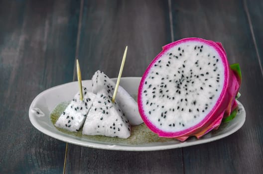 Ripe Dragon fruit  with slice on dish over wooden background , still life