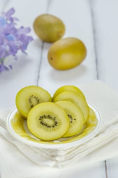 golden kiwi fruit and sliced on dish over white wooden background