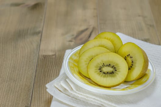golden kiwi fruit and sliced on dish over wooden background