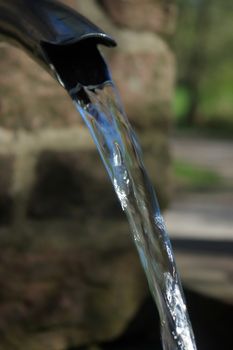 Close up of running water from a tap with brick wall on background