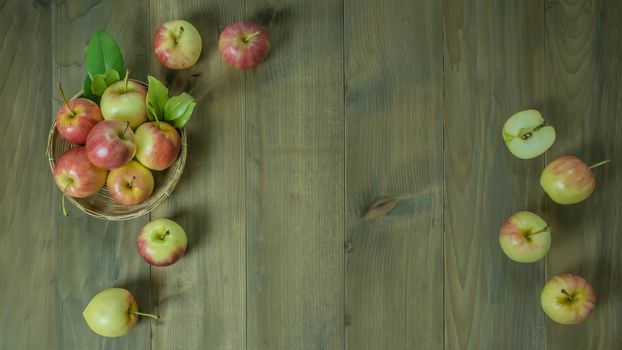 Top view red and yellow apple with leaves and  bamboo basket on wooden background with free space for text
