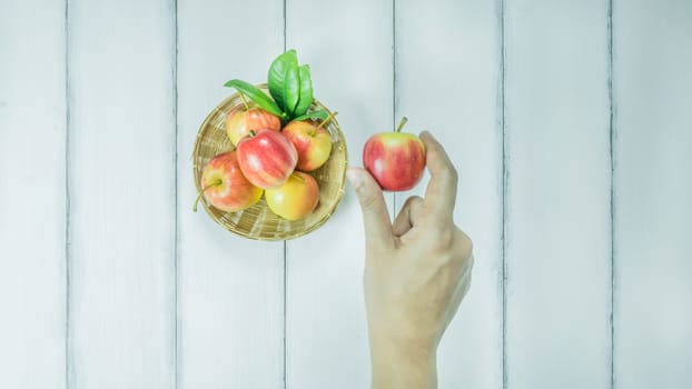 Top view red and yellow apple with leaves and  bamboo basket on  white wooden background with free space for text