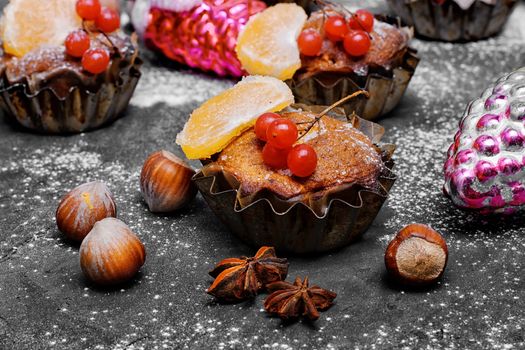 few Christmas cupcakes with fruits on black background