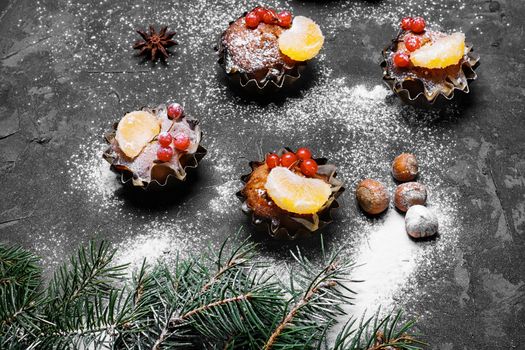 few Christmas cupcakes with fruits on black background
