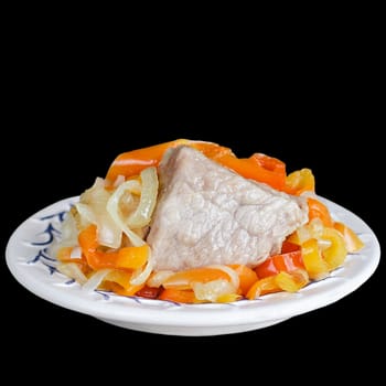 Piece of pork with steamed vegetables on plate, isolated on a black background. Place for text.