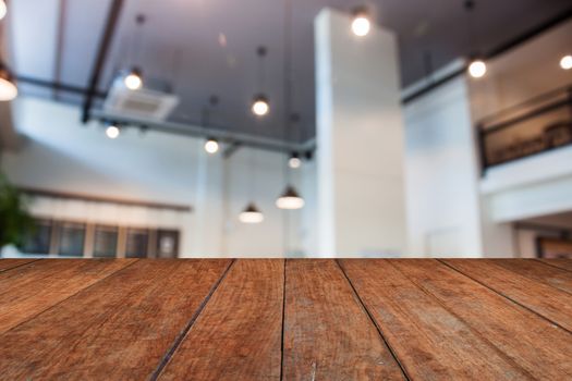 Brown wooden table top with abstract blur coffee shop interior for background