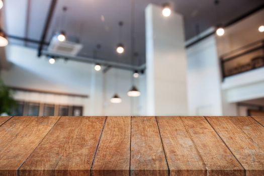 Perspective wooden table top with abstract blur coffee shop interior for background