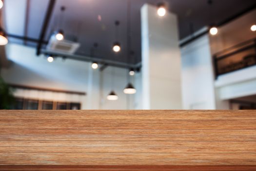 Top of wooden table with abstract blur coffee shop interior for background